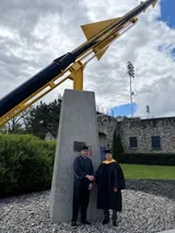 Me in my cap and gown, shaking hands with Dr. Devinder Kaur, my supervisor, beneath the rocket monument on campus.