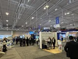 The exhibit hall from one of the aisles I walked, rows of stands under the hall’s roof trusses.